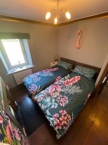 a bedroom with two beds and a window at Flosh Cottage Lake District in Cleator