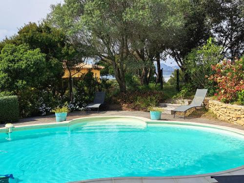 une grande piscine bleue avec 2 chaises et des arbres dans l'établissement Rez de jardin villa Presqu'ile de Giens, à Hyères