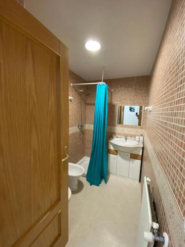 a bathroom with a toilet and a blue shower curtain at El Diamante Soldeu in Soldeu