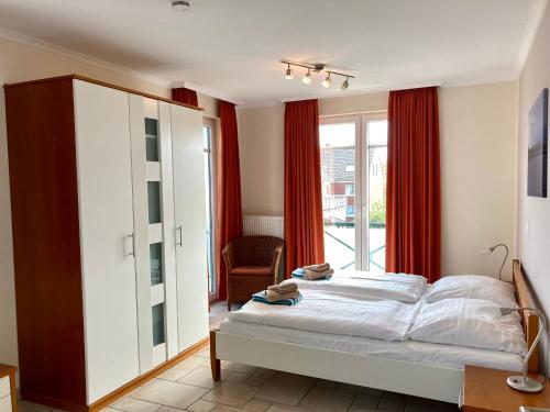 ein Schlafzimmer mit einem Bett und einem großen Fenster in der Unterkunft Villa Puccini Whg. 4 in Wangerooge