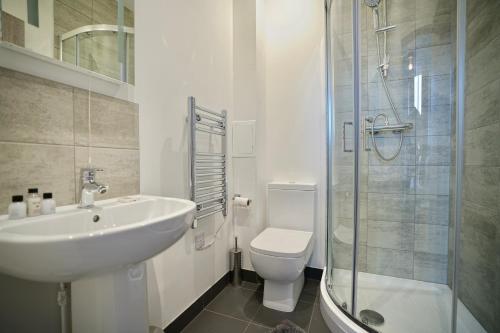 a bathroom with a sink and a toilet and a shower at Large Balcony Apartment with City View by DH ApartHotels in Peterborough