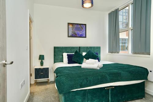a bedroom with a large bed with a green blanket at Large Balcony Apartment with City View by DH ApartHotels in Peterborough