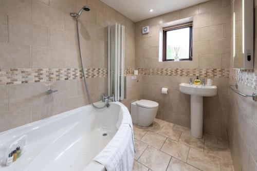 a bathroom with a tub and a toilet and a sink at Fisher Gill, Sebergham, Nr Caldbeck in Sebergham