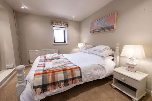 1 dormitorio con cama blanca y mesita de noche con lámpara en Fisher Gill, Sebergham, Nr Caldbeck, en Sebergham