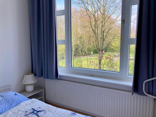 - une chambre avec un lit et une fenêtre avec des rideaux bleus dans l'établissement Residenz am Rosengarten 16, à Wangerooge