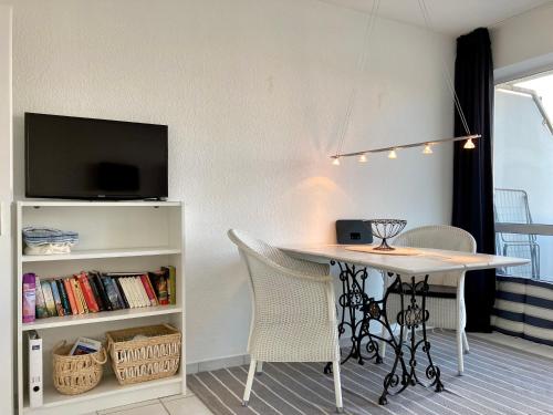 ein Esszimmer mit einem Tisch und Stühlen sowie einem TV in der Unterkunft Haus Seeluft Whg 11 in Wangerooge