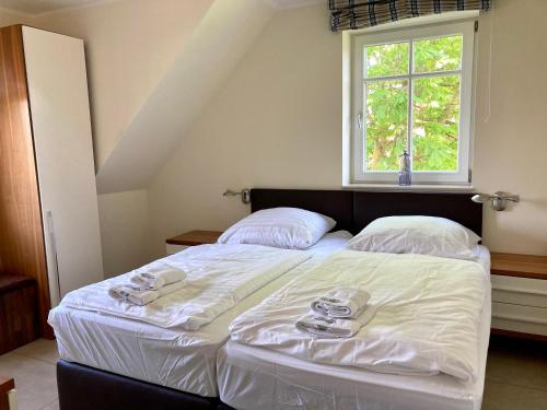 a bedroom with a bed with white sheets and a window at Ferienhaus Grodenblick Sanddorn Whg 3 in Wangerooge