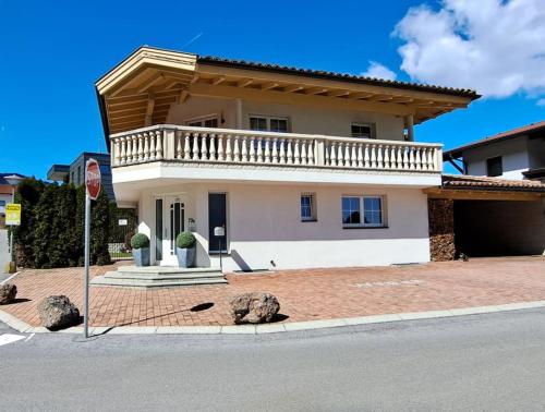 a white house with a balcony on a street at DSW Ferienhaus in Oberperfuss