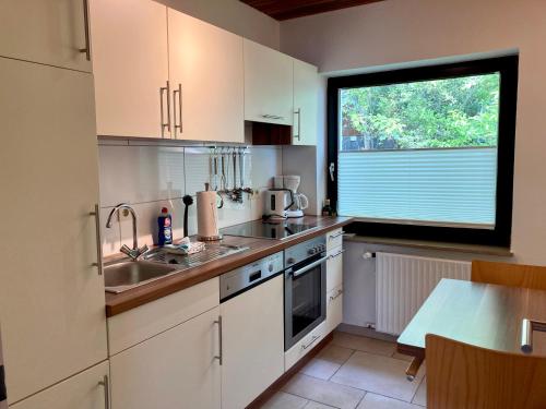 eine Küche mit weißen Schränken, einem Waschbecken und einem Fenster in der Unterkunft Haus Wilhelmi Wilhelmi Whg 2 in Wangerooge