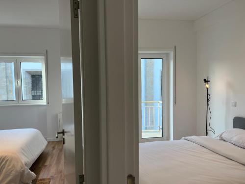 a white bedroom with two beds and two windows at Braga Centro, Totalmente remodelado em 2023! in Braga