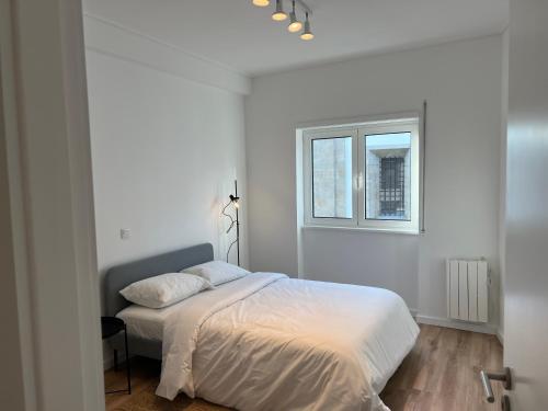 a white bedroom with a bed and a window at Braga Centro, Totalmente remodelado em 2023! in Braga