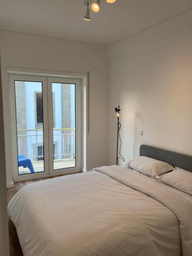 a white bedroom with a bed and a window at Braga Centro, Totalmente remodelado em 2023! in Braga