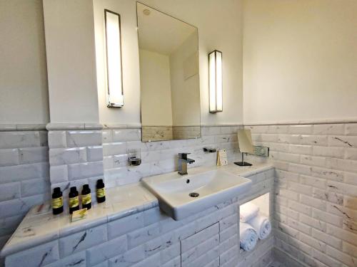 a white bathroom with a sink and a mirror at VALLÉE 1900 in Torfou