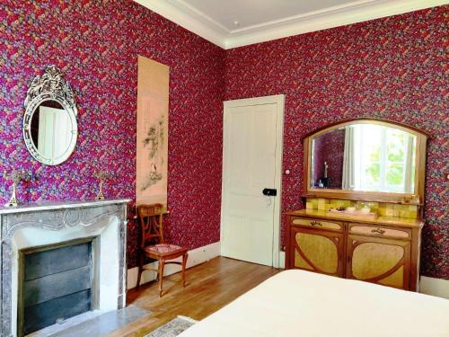 a bedroom with red walls with a fireplace and a mirror at VALLÉE 1900 in Torfou