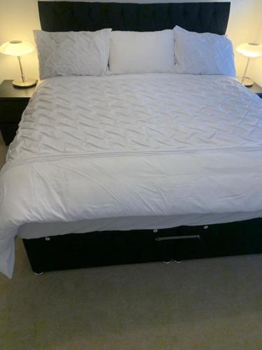 a large bed with white sheets and pillows at Brand New Posh 1 Bed Lakeside Flat No parties No Events in West Thurrock