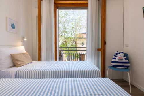 Duas camas num quarto com uma janela e uma cadeira em Nida 18 em Cattolica