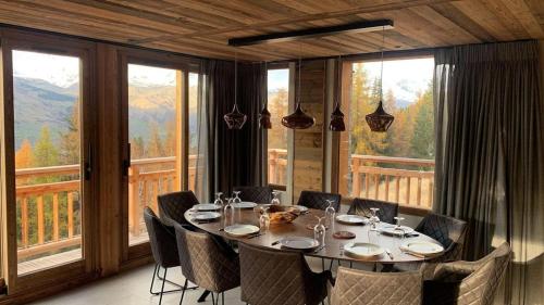 une salle à manger avec une table et des chaises et une grande fenêtre dans l'établissement La Charrue, Luxury chalet (10p) 5 bedrooms, à Peisey-Nancroix