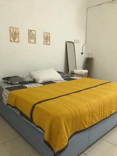 een slaapkamer met een bed met een gele deken erop bij Solehah Homestay in Seri Iskandar