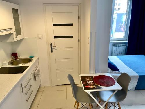a small kitchen with a table and chairs and a bed at ComeWa Apartments in Warsaw