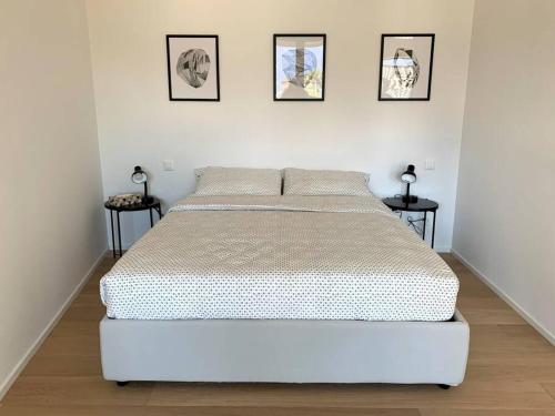 a white bed in a bedroom with three pictures on the wall at LAKE in Lugano