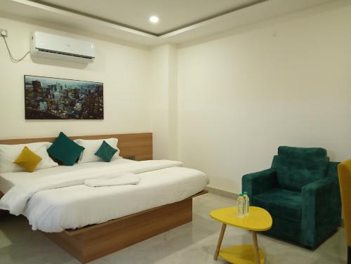 a bedroom with a bed and a green chair at Hotel New Centro in Gulbarga
