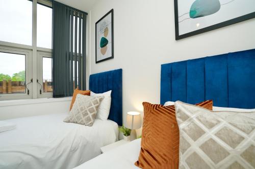 a bedroom with two beds and a blue headboard at Bayard Plaza in Peterborough