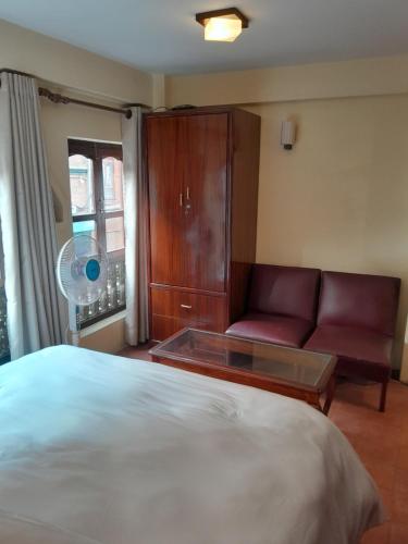 a bedroom with a bed and a couch and a window at Studio Apartment at UNESCO Heritage Site in Kathmandu