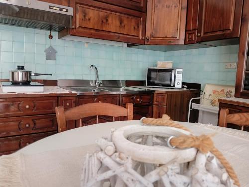 a kitchen with wooden cabinets and a counter top with a table at Il Giardino in Baunei