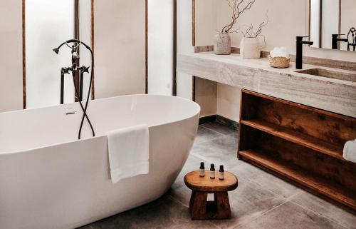 La salle de bains est pourvue d'une baignoire blanche et d'un tabouret en bois. dans l'établissement Le Sidi - A TLT Signature Hotel, à El Alamein