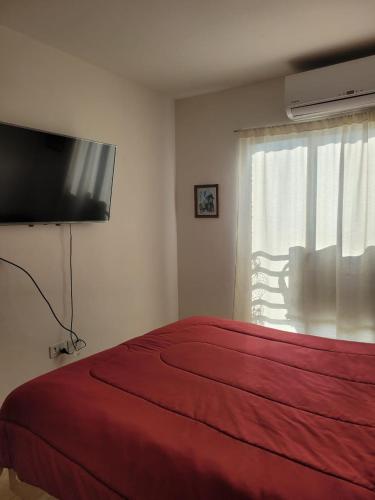 1 dormitorio con cama roja y TV de pantalla plana en Departamento Corrientes capital en Corrientes