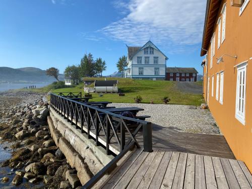 a house with picnic tables on a walkway near the water at Sandtorgholmen Glamping in Sandtorv