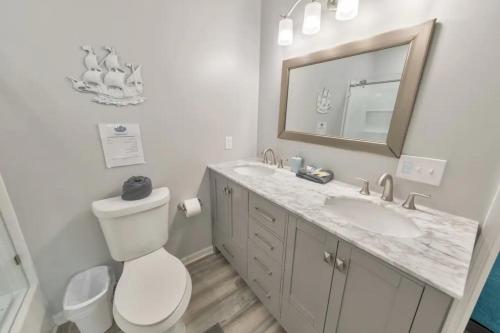 a bathroom with a toilet and a sink and a mirror at Sandy Feet Retreat in Panama City Beach
