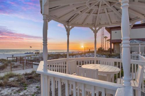 a porch with a gazebo and the beach at sunset at Sandy Feet Retreat in Panama City Beach