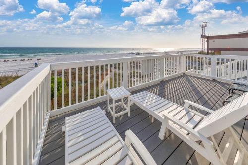 a balcony with two white chairs and the beach at Sandy Feet Retreat in Panama City Beach