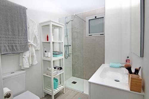 La salle de bains blanche est pourvue d'une douche et d'un lavabo. dans l'établissement Marina Real I, à Dénia