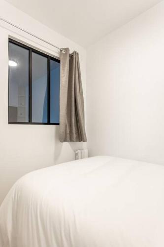 une chambre avec un lit blanc et une fenêtre dans l'établissement NidAudonnien, à Saint-Ouen