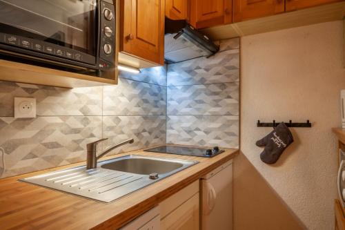 une cuisine avec un évier et un micro-ondes dans l'établissement Corniche B10 - Studio rénové avec coin montagne à 650m des pistes, à Morzine