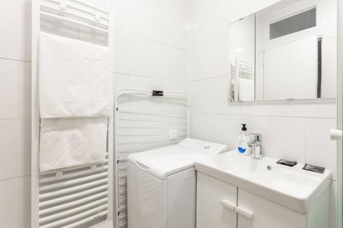 ein weißes Badezimmer mit einem Waschbecken und einem Spiegel in der Unterkunft NidAudonnien in Saint-Ouen