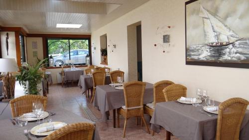 a restaurant with tables and chairs and a boat painting on the wall at Les Ondines in Saint-Guénolé