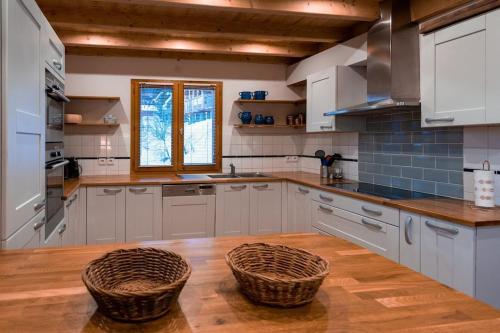 une cuisine avec des armoires blanches et des paniers sur une table en bois dans l'établissement Ekseption - 7-room chalet + sauna 12/14 persons, à Peisey-Nancroix