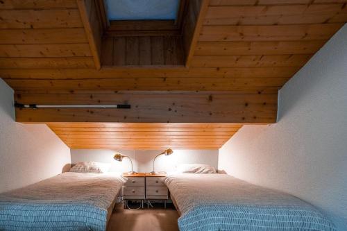 deux lits dans une chambre avec plafonds en bois dans l'établissement Ekseption - 7-room chalet + sauna 12/14 persons, à Peisey-Nancroix