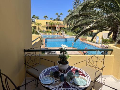 einen Tisch und Stühle mit Poolblick in der Unterkunft Atlantic Garden Andrew apartments Pool air conditioning in Corralejo