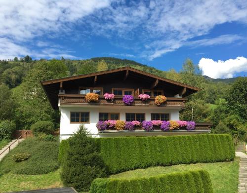 ein Haus mit Blumen auf dem Balkon in der Unterkunft Landhaus Bergner Alm in Bruck an der Großglocknerstraße