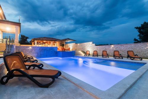 einen Pool mit Liegestühlen neben einem Haus in der Unterkunft Luxurious Villa Istra Kamen in Pula
