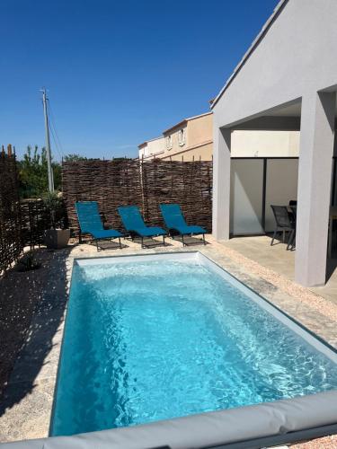 a swimming pool with blue chairs in a backyard at Les jardins de la Gravière à 5 mn de Lourmarin avec piscine privée in Puyvert