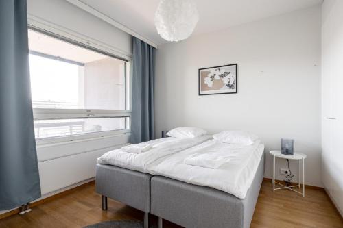 a white bedroom with a bed and a window at Top Floor 1BR Apartment in Tampella with Free Parking, Sauna & Balcony - Hosted by 2ndhomes in Tampere