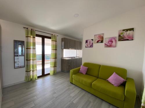 a living room with a green couch and a kitchen at Nora's Flats in Triscina