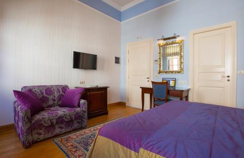 a bedroom with a purple bed and a chair and a table at Aetoma Hotel in Nafplio