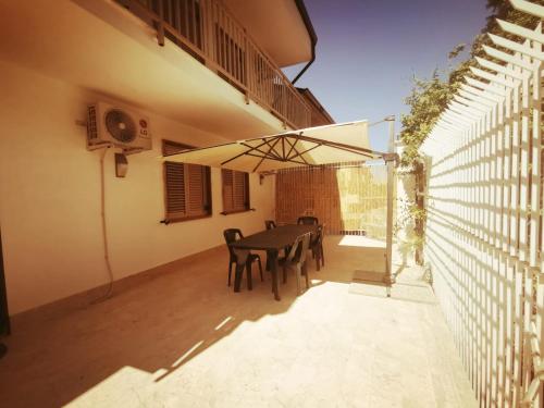 un patio con mesa, sillas y una valla en KALOS B&B, en Campobello di Licata