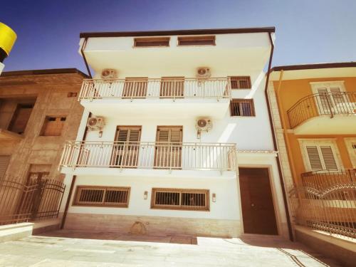 un edificio blanco con balcones en un lateral en KALOS B&B, en Campobello di Licata